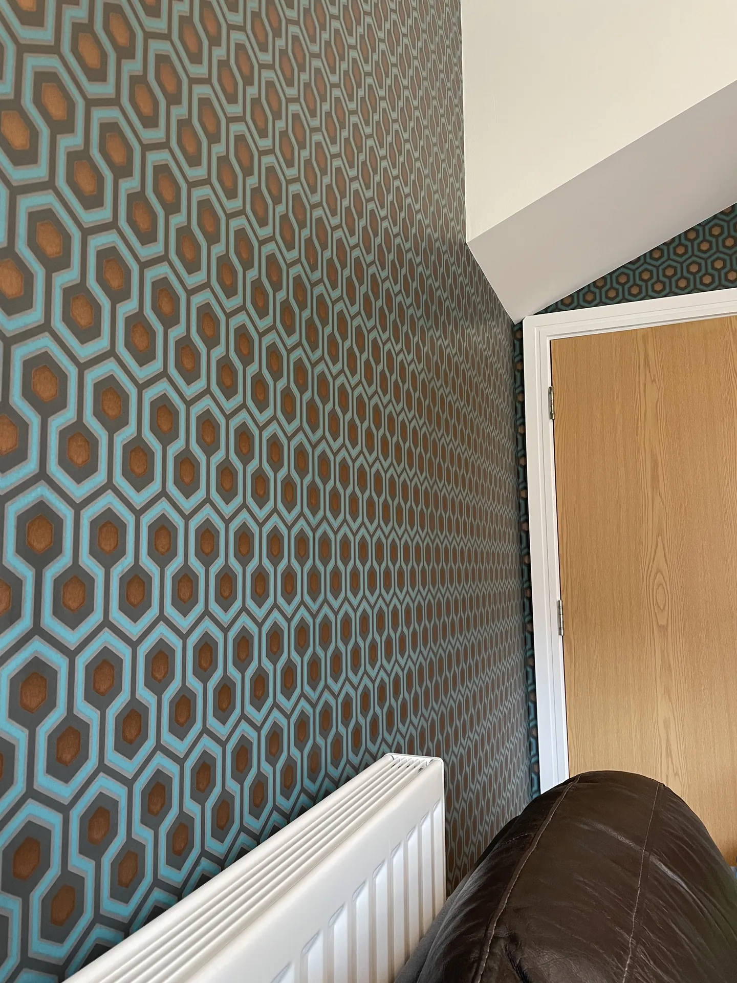 Muswell Hill entrance stairwell hung with bold Hicks Hexagon wallpaper across walls and stair rise opening view